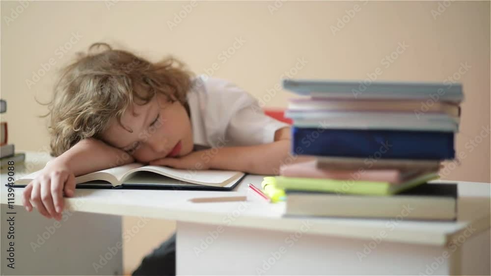 A child of primary school age do homework. The boy does his homework at his desk at home.pupil has been bored on the lesson A child of primary school age do homework. The boy does his homework at his desk at home.pupil has been bored on the lesson