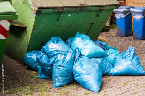 Gestapelte blaue Müllsäcke am Container photo