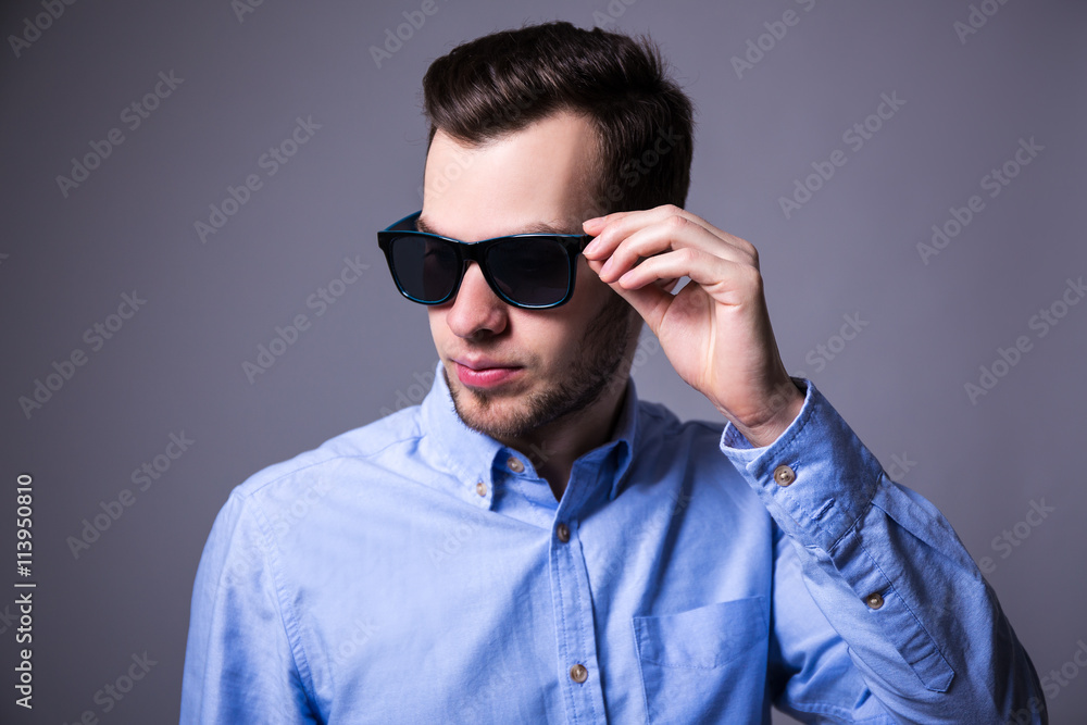 portrait of young handsome man in sunglasses over gray portrait of young handsome man in sunglasses over gray