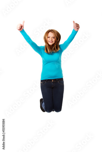 Young woman jumping with thumbs up