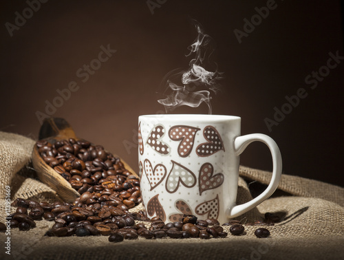 Cup with heart and coffee beans on dark background