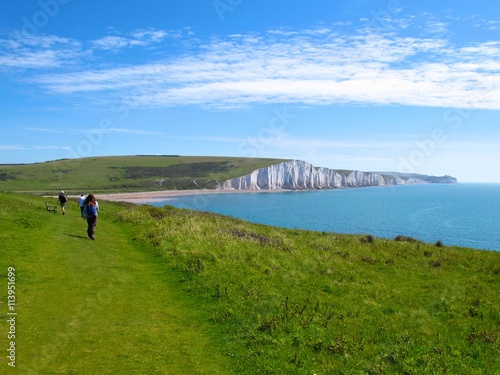 Hikers approach white cliffs of the Seven Sisters in Eastbourne, East Sussex, England