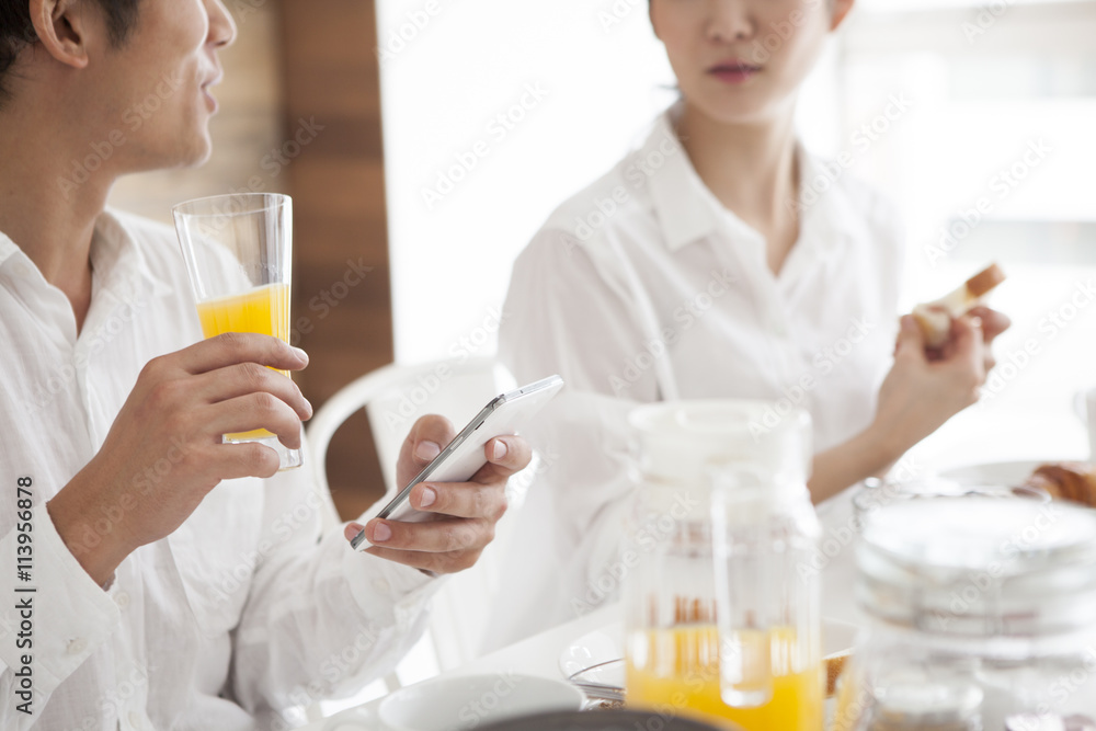 The man is eating breakfast with a smartphone The man is eating breakfast with a smartphone