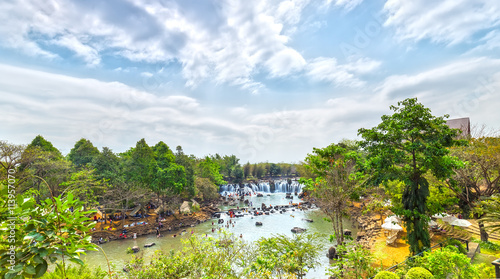Giang Dien Waterfall above with water pouring down billowing white  surrounded by a forest covered attract many tourists to the resort  above the beautiful cloudy sky sunny day fresh welcome freshness