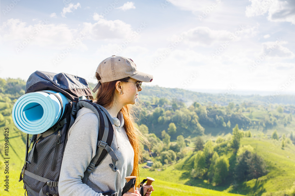 Young hiking woman with backpack and poles
