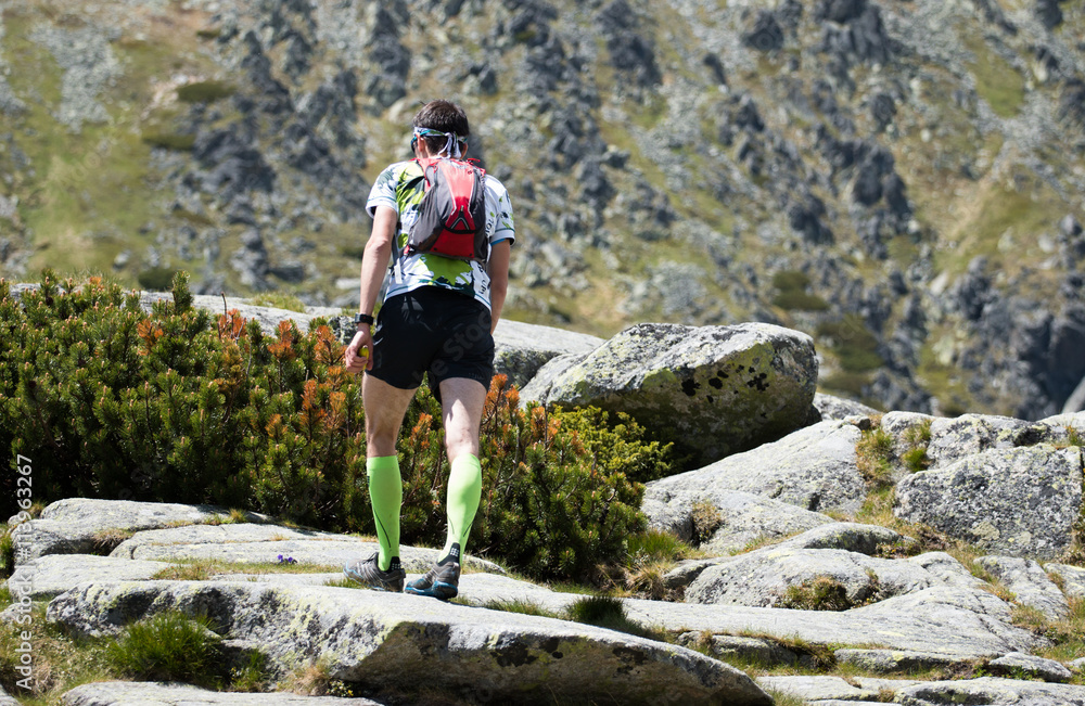 trail runner man with backpack in the race in high mountain scenery