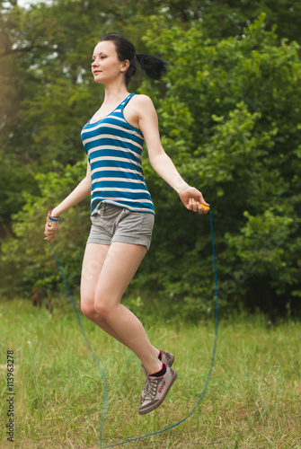 smiling girl exercises with a skipping rope outdoors