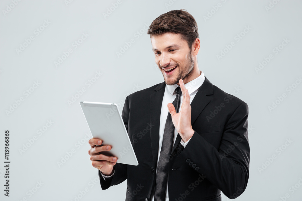 Smiling young businessman using tablet and making video conference Smiling young businessman using tablet and making video conference