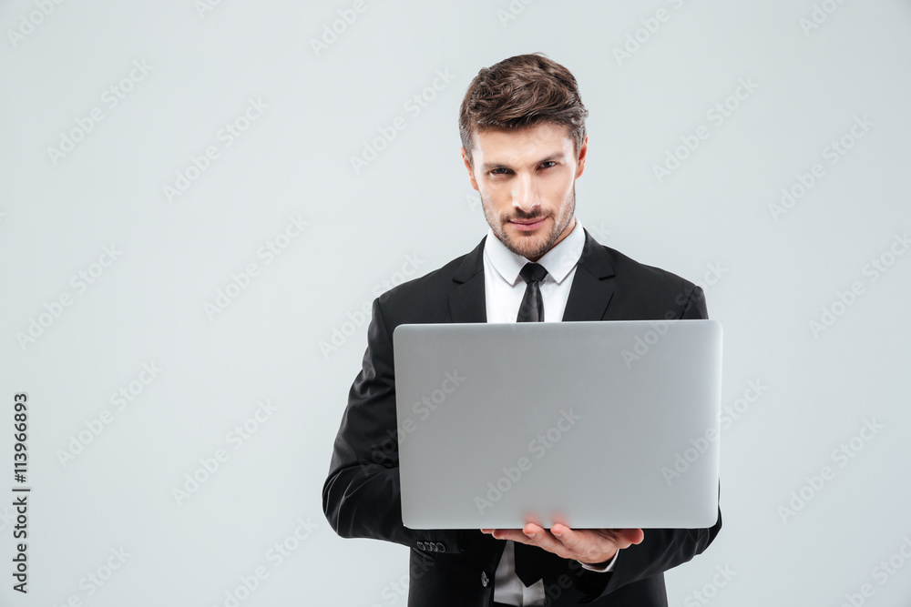 Confident young businessman in suit and tie using laptop Confident young businessman in suit and tie using laptop