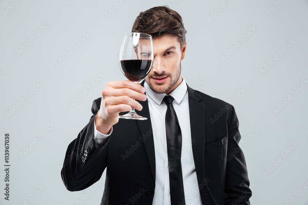 Focused young male sommelier looking at red wine in glass Focused young male sommelier looking at red wine in glass