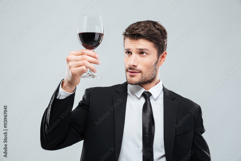Serious man sommelier in suite tasting red wine in glass Serious man sommelier in suite tasting red wine in glass