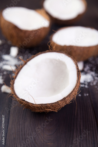 Coconut halves with shell on a dark wooden background