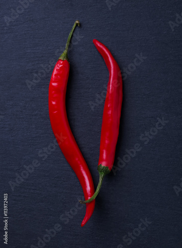 Two hot chili peppers on black background