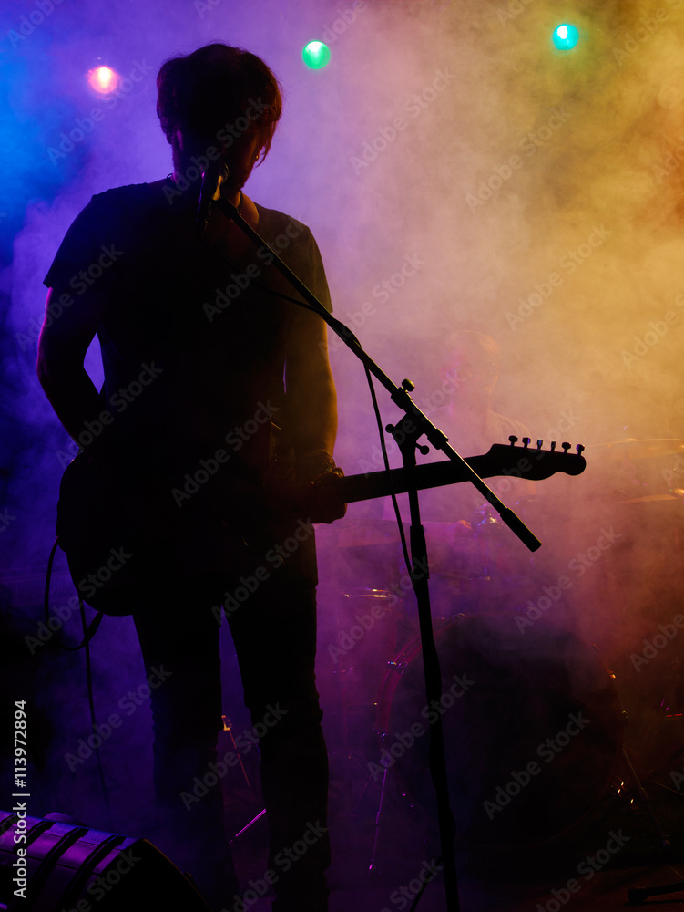 Silhouette of guitar player on stage.