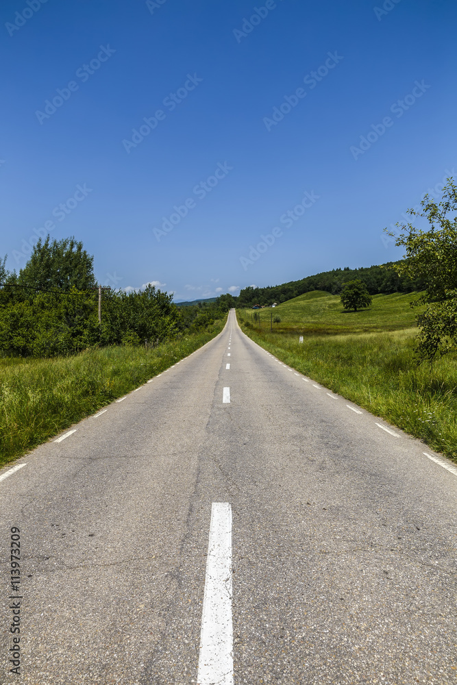 Empty asphalt road in countryside, bend of road, field in the ba