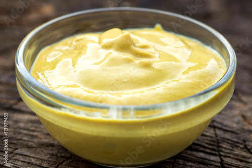 Mustard sauce in glass bowl on wooden background
