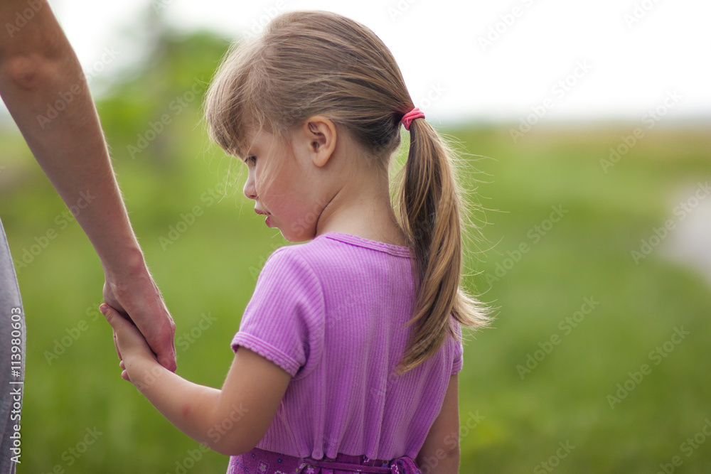 Little girl holding a hand of her mother. Family relations conce Little girl holding a hand of her mother. Family relations conce