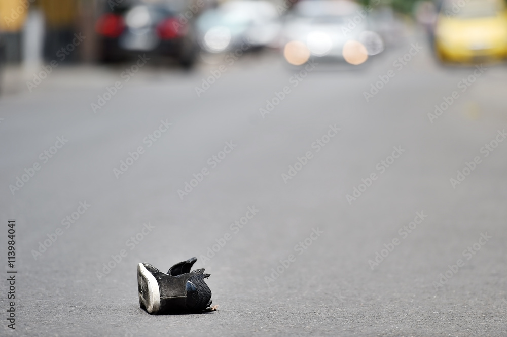 Shoe on the street with cars in background after accident Shoe on the street with cars in background after accident