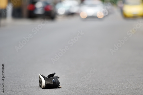 Shoe on the street with cars in background after accident