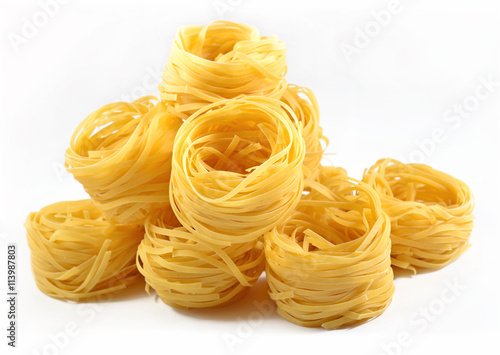 Uncooked Italian pasta tagliatelle nests on a white