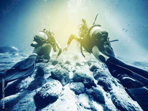 Fototapeta Two divers swimming close to the ocean floor.