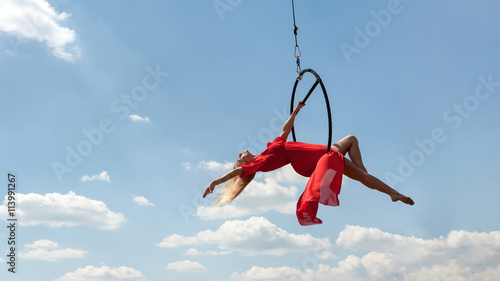 Graceful acrobat performs gymnastic trick on hoop © alexsfoto