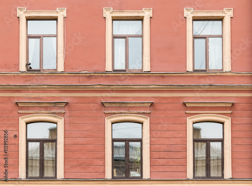 Several windows in a row on facade of urban apartment building front view, St. Petersburg, Russia.