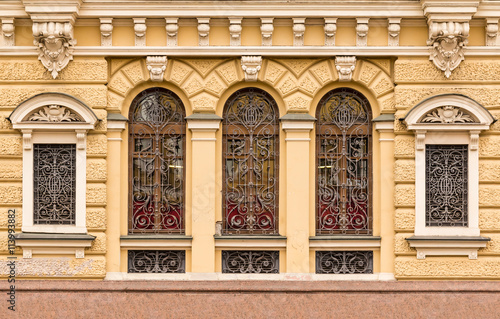 Several windows in a row with wrought grate on facade of urban office building front view, St. Petersburg, Russia