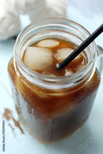 Glass jar of iced coffee on wooden table