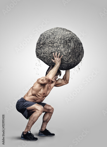 Shirtless muscular male holding big stone. photo