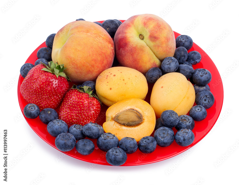 Fresh blueberry, strawberry, peach and apricot on a red plate Fresh blueberry, strawberry, peach and apricot on a red plate