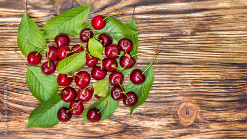 Cherries with leaves on the wooden background