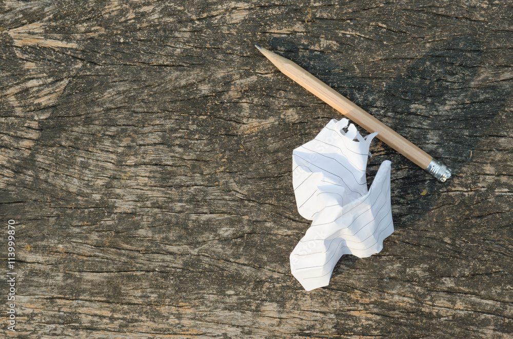 crumpled paper and used pencil on wood background crumpled paper and used pencil on wood background