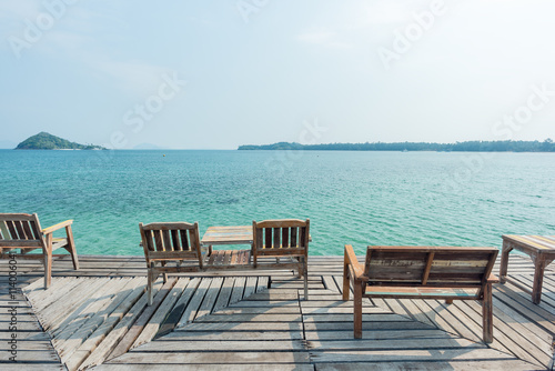 Wooden chair on wooden floor with beautiful ocean and blue sky scenery © yotrakbutda