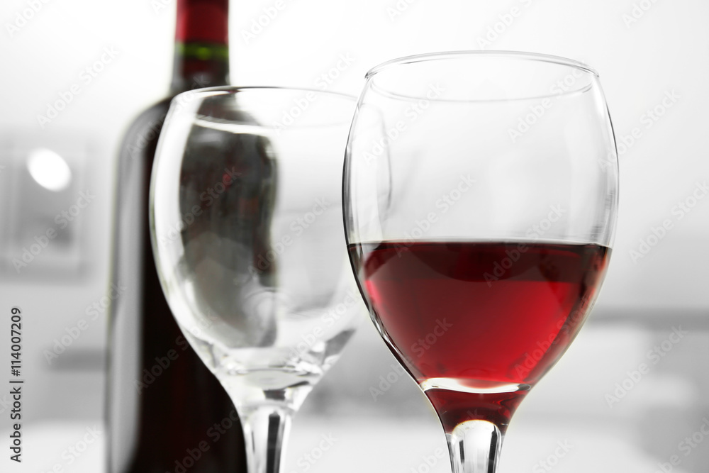 Glass of red wine with bottle on blurred interior background Glass of red wine with bottle on blurred interior background