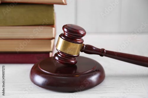 Gavel with books on wooden table closeup