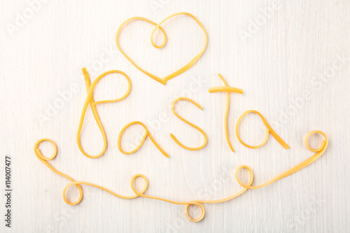 Word PASTA made of cooked spaghetti on wooden background