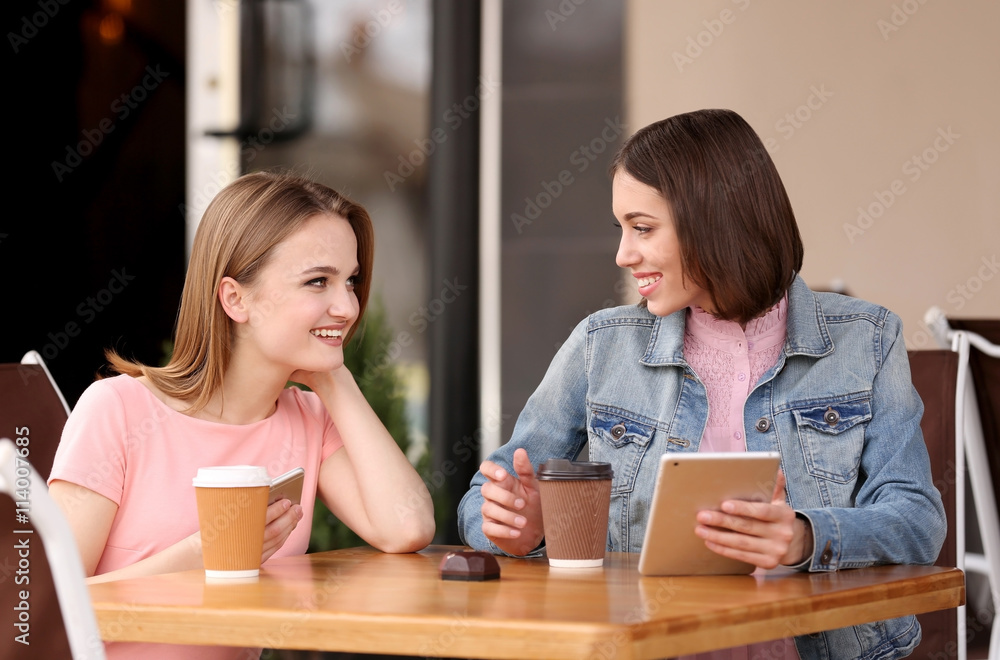 Young happy women drinking coffee and talking in cafe Young happy women drinking coffee and talking in cafe