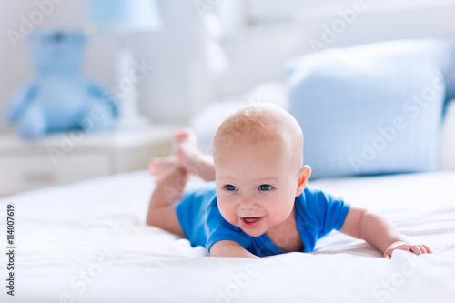 Baby boy in white sunny bedroom