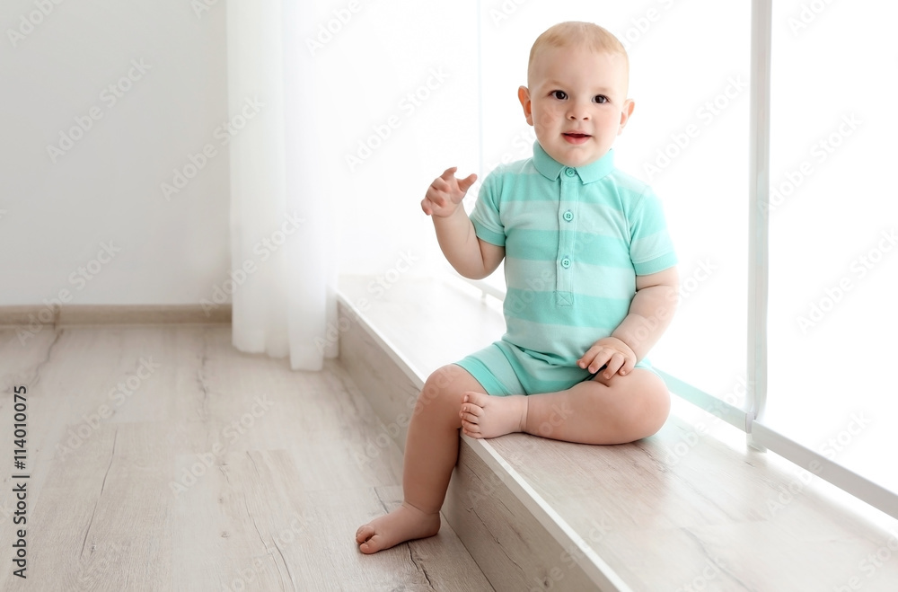 Baby boy sitting on the window indoors Baby boy sitting on the window indoors