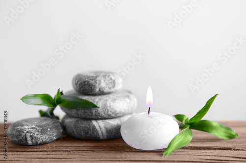 Gray spa stones with candle on light background