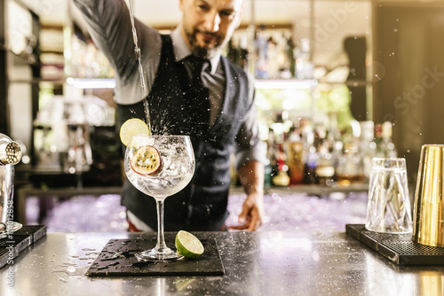 Barman is making cocktail at night club. photo