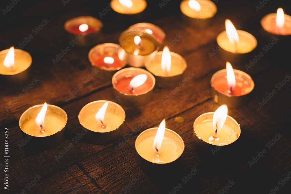 Group of lit candles in the night, on wooden plank background Group of lit candles in the night, on wooden plank background
