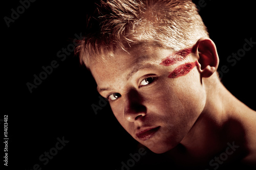 Serious boy with red painted lines on head