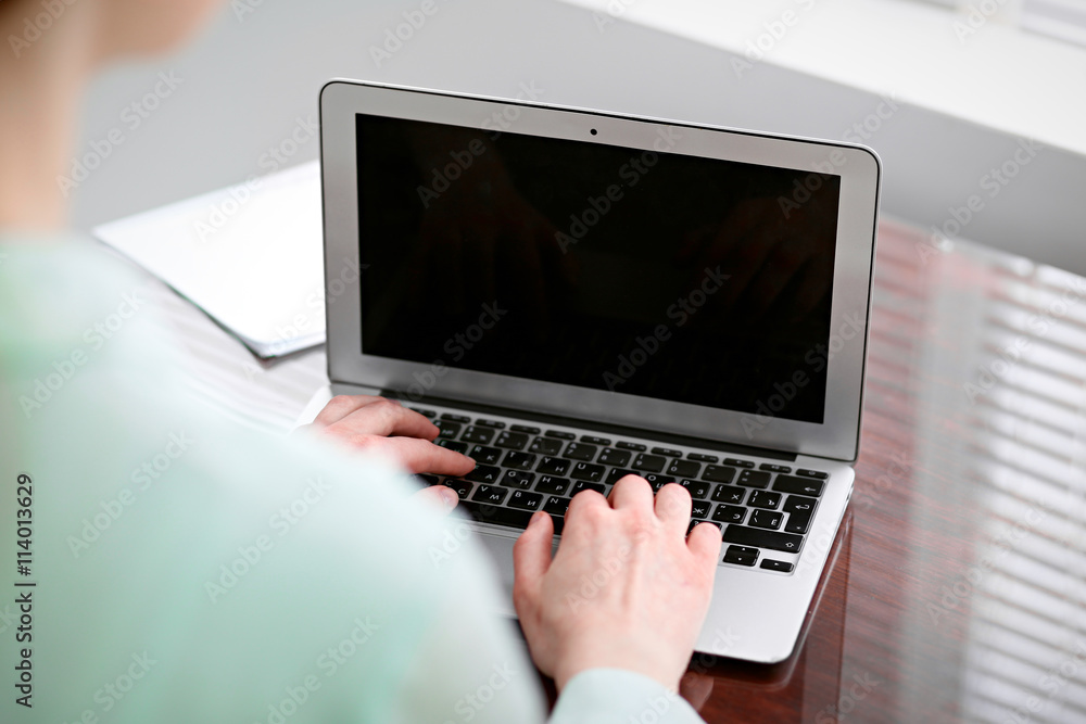 Business woman hands in a green blouse sitting at the desk in the office and typing on the laptop . Business woman hands in a green blouse sitting at the desk in the office and typing on the laptop .