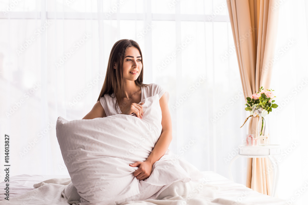 Happy woman holding pillow on the bed at home Happy woman holding pillow on the bed at home