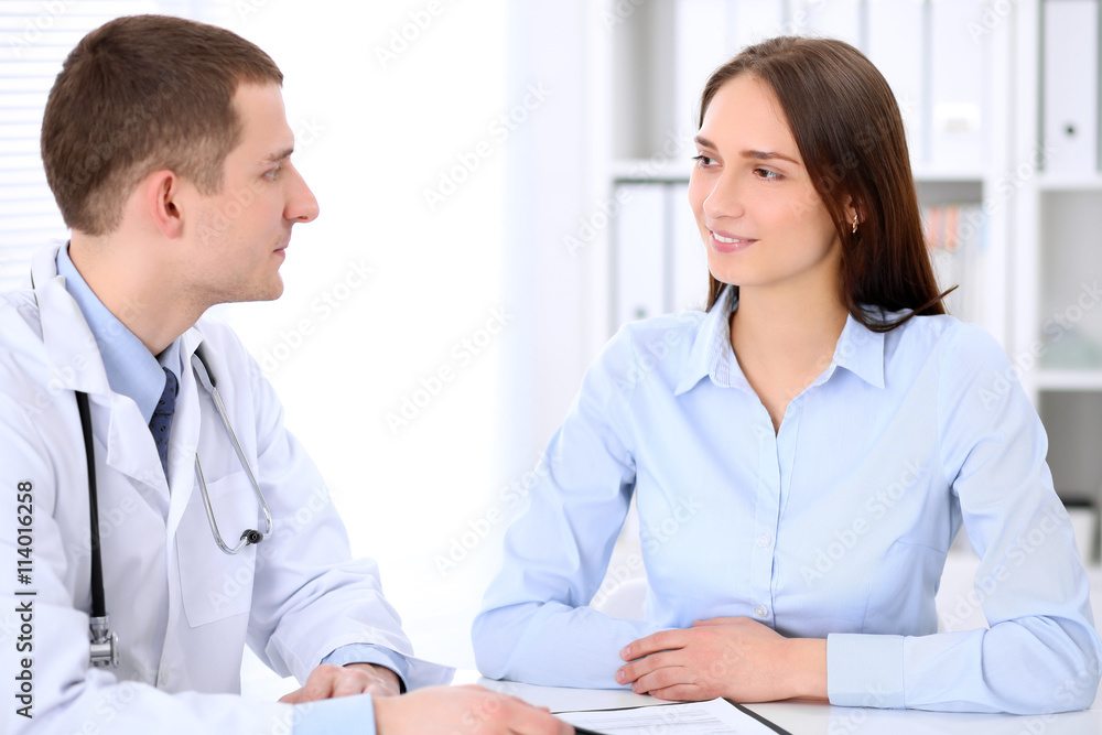 Doctor and patient sitting at the table in medical cabinet. High level and quality medical service concept. Doctor and patient sitting at the table in medical cabinet. High level and quality medical service concept.