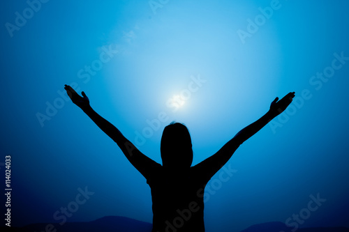 Photographie Silhouette of woman on a summit with upraised arms on the top mo