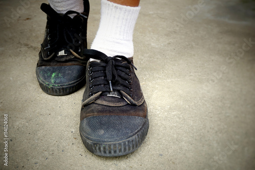 poor Asian student going back to school wears old worn black leather shoes. vintage tone 