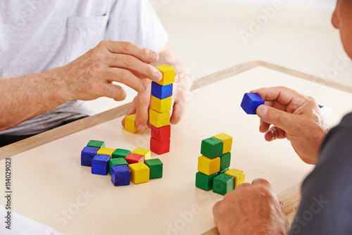 Hände von Senioren mit Demenz bauen Turm